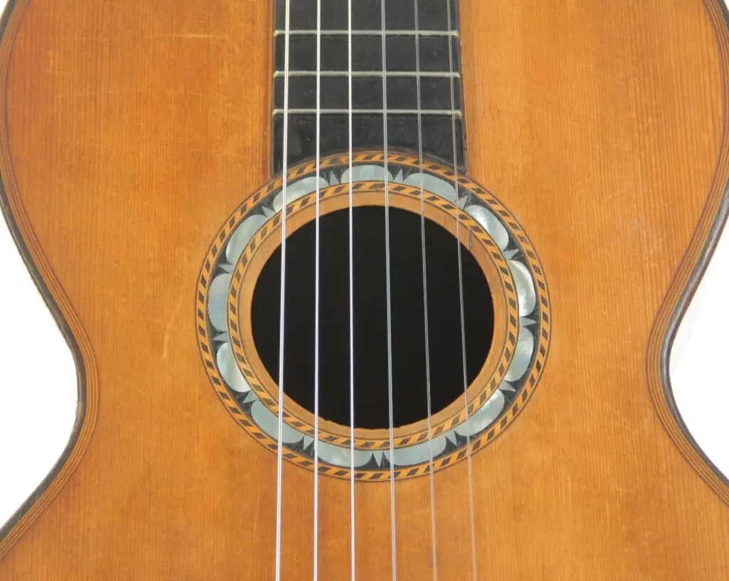 Nahaufnahme Der Französischen Romantikgitarre Von Ca. 1860. Zu Sehen Sind Ihr Holzkorpus, Die Dekorative Rosette Um Das Schallloch, Die Saiten Und Ein Teil Des Griffbretts.