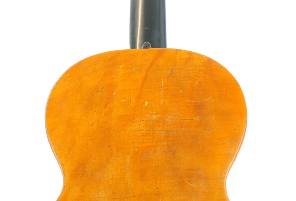 Nahaufnahme Der Rückseite Der Französischen Romantikgitarre Von ~1860 Mit Zerkratzter, Abgenutzter Gelblich-Brauner Holzoberfläche Und Einem Nach Oben Ragenden Schwarzen Hals.