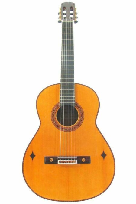 The Alberto Pantoja Martin 2012 Flamenco Guitar is a classical acoustic guitar with a light wood body, dark fretboard, tuning pegs, and two diamond-shaped inlays near the bridge, shown on a white background.