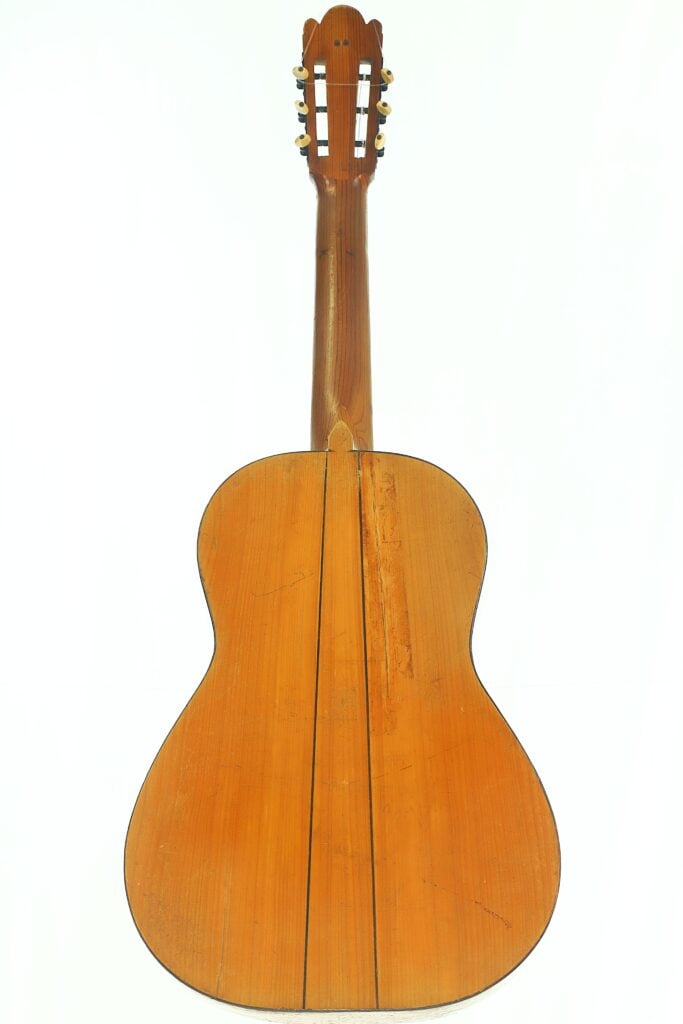 Die klassische Gitarre „José Ortega ~1890“ wird von hinten gezeigt, wobei ihr Holzkorpus, der Hals und die Kopfplatte mit den Stimmwirbeln vor einem weißen Hintergrund besonders hervorgehoben werden. Die klassische Gitarre „José Ortega ~1890“ wird von hinten gezeigt, wobei ihr Holzkorpus, der Hals und die Kopfplatte mit den Stimmwirbeln vor einem weißen Hintergrund besonders hervorgehoben werden.