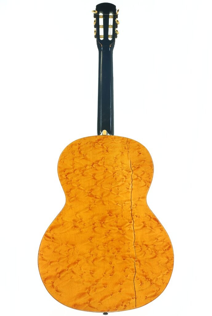 Die Rückansicht der A. Klein-Akustikgitarre aus der Zeit um 1920 zeigt eine glänzende, helle Holzoberfläche mit natürlicher Maserung und einem schwarzen Hals. Die Rückansicht der A. Klein-Akustikgitarre aus der Zeit um 1920 zeigt eine glänzende, helle Holzoberfläche mit natürlicher Maserung und einem schwarzen Hals.