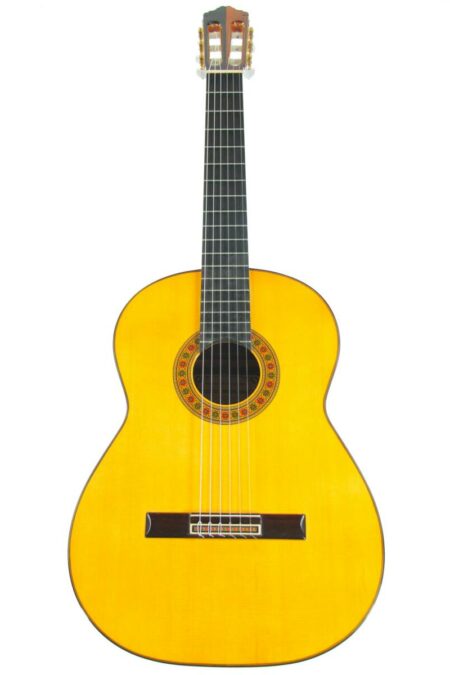 A Miguel Rodriguez 1992 Church Door Classical Guitar with a light wood body and six strings stands upright against a white background.