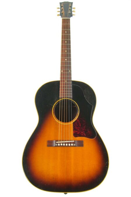 Gibson Lg-2 1957 Acoustic Guitar is a sunburst acoustic guitar with a dark edge fading to warm amber, six strings, a tortoiseshell pickguard, and a wooden bridge.