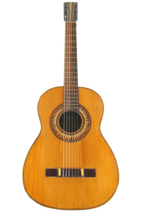 The Jaime Ribot 1900 Classical Guitar features a light wood body, dark neck, six strings, and a decorative circular rosette around the sound hole.