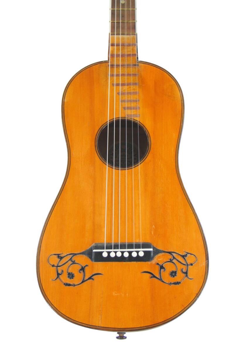 The Image Shows The Front Of A Karl Frey Baroque Guitar, Featuring A Light Brown Wooden Body, Six Strings, A Round Sound Hole, And Black Decorative Designs Near The Bridge.