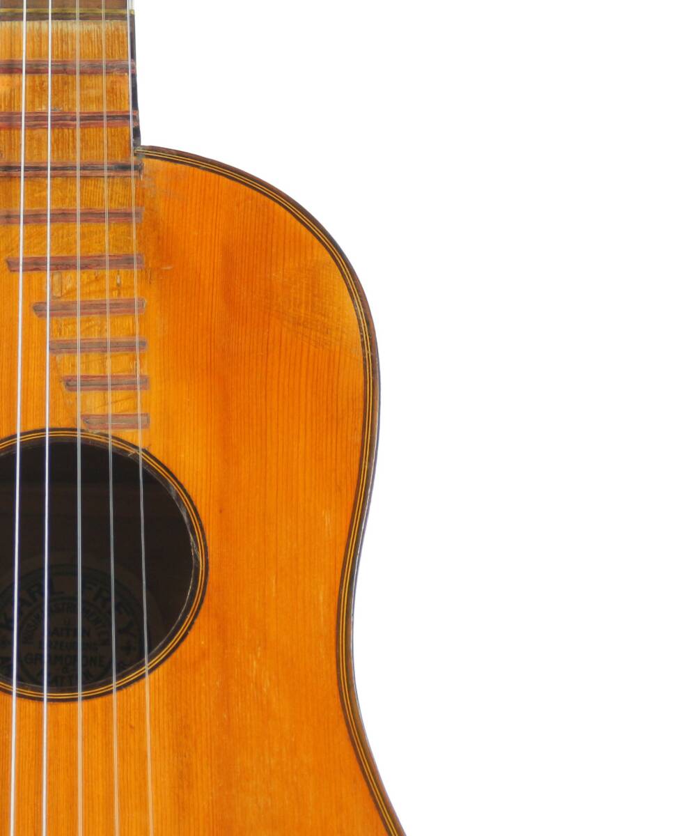 Close-Up Of The Karl Frey Baroque Guitar’s Upper Section, Highlighting The Strings, Sound Hole, And Part Of Its Wooden Body Against A White Background.