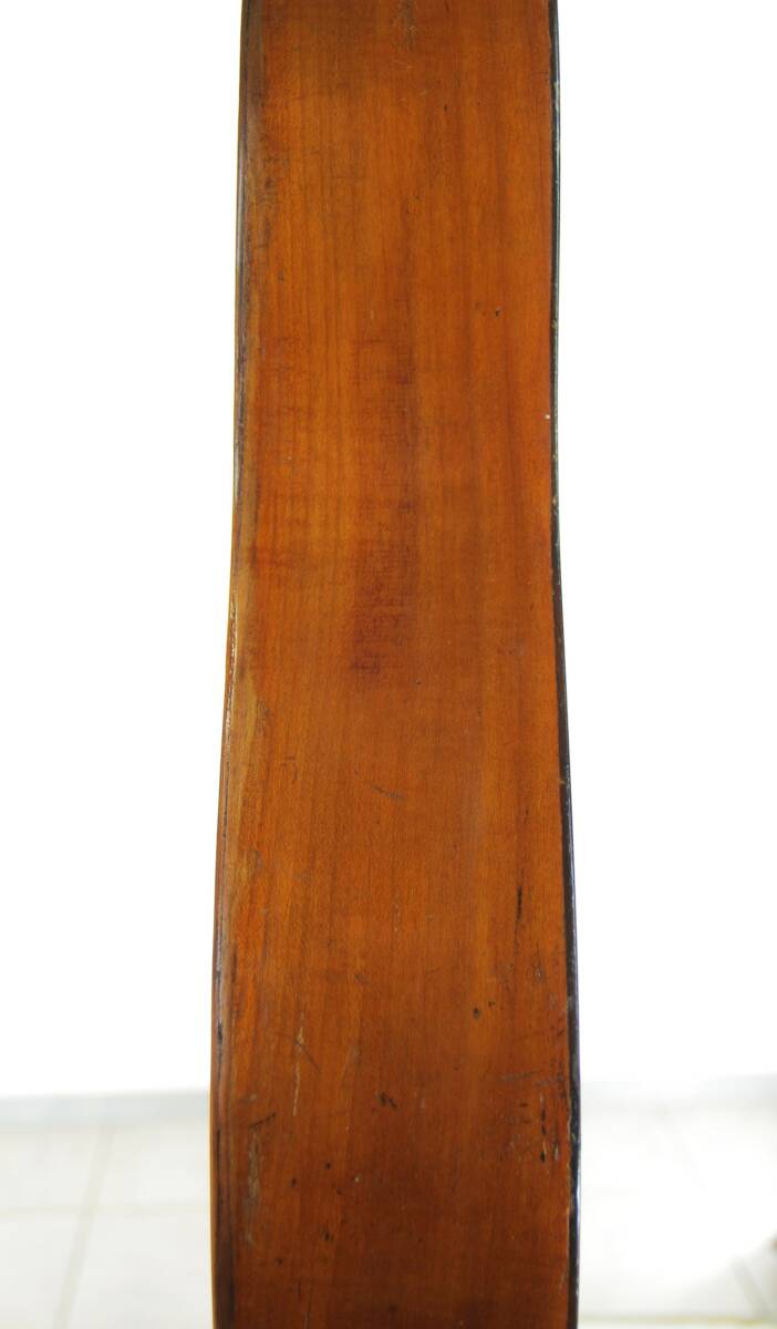 A Close-Up Of The Karl Frey Baroque Guitar Highlights Its Curved, Polished Wooden Side With A Smooth Finish And Distinct Grain Patterns Set Against A White Background.