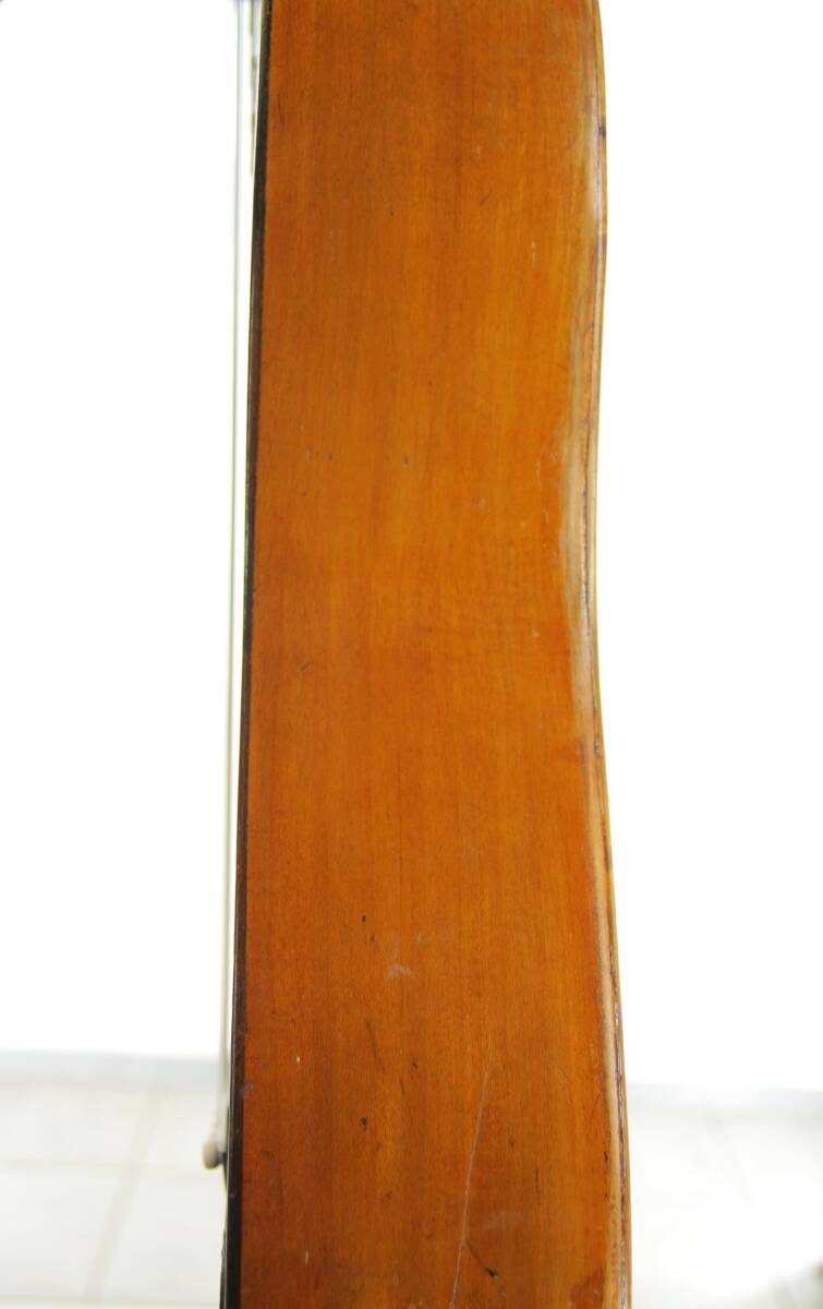 Close-Up Side View Of The Karl Frey Baroque Guitar, Showcasing Its Polished Wooden Surface With Minor Scratches Against A White Background.