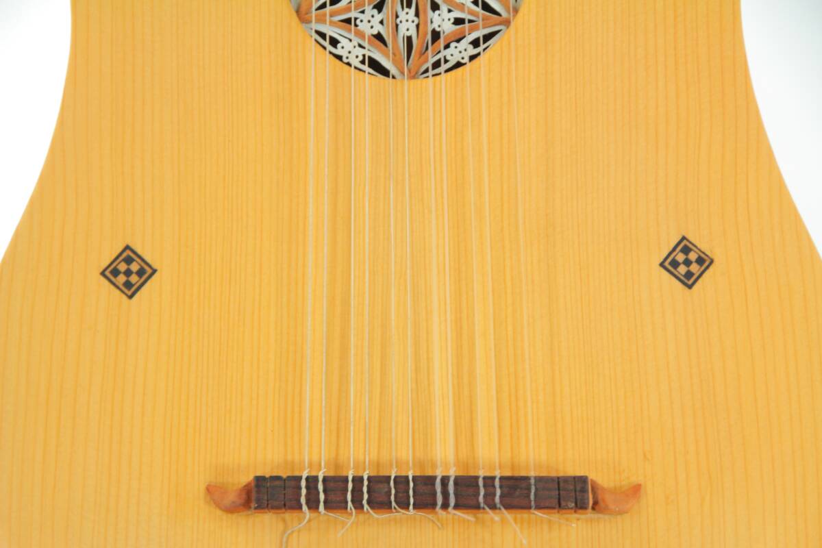 Close-Up Of The Luis Milan Vihuela 1535/36 Body, Featuring Eight Strings, A Decorated Sound Hole, Two Diamond-Shaped Inlays, And A Wooden Bridge On Light-Colored Wood.