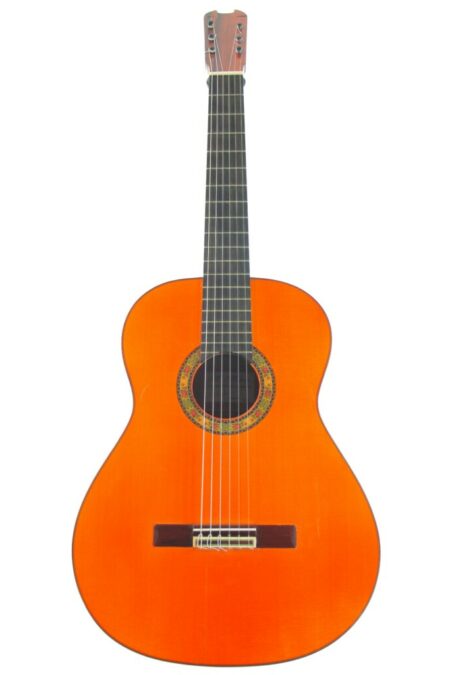 A Miguel Molero 2012 negra Flamenco Guitar featuring a natural orange-brown finish, six strings, black fretboard, and decorative rosette, shown against a white background.