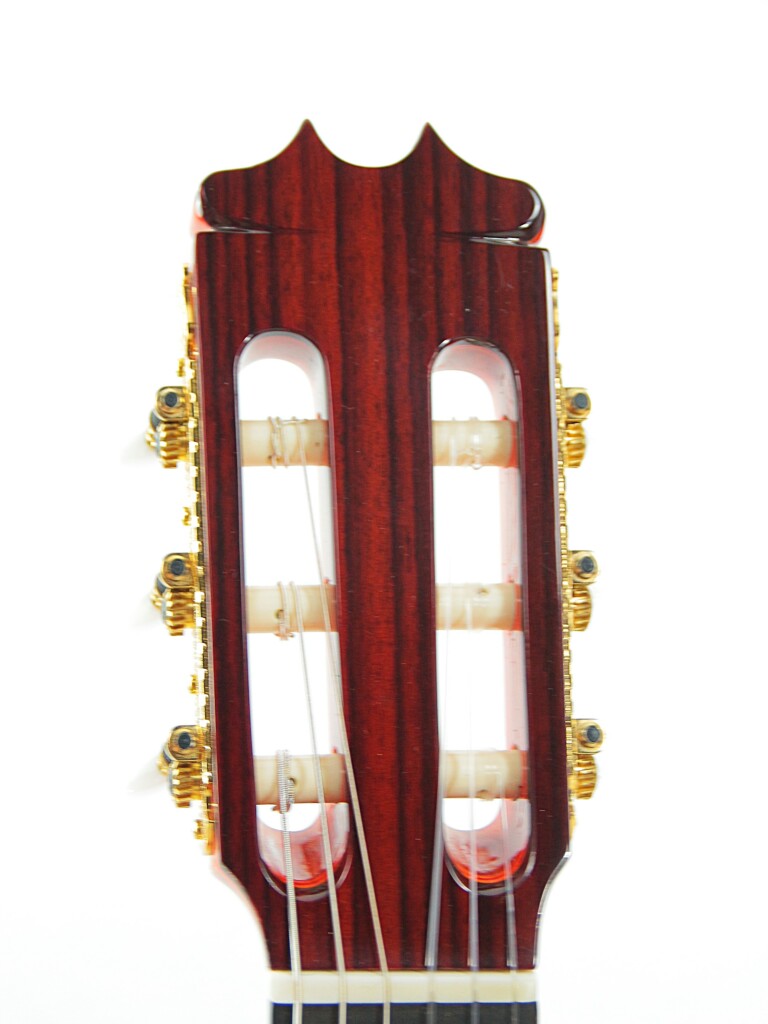 Nahaufnahme Einer Hermanos Conde 1999 Paco De Lucia Spezial Flamenco Gitarre Mit Dunkler Holzoberfläche, Goldenen Mechaniken Und Nylonsaiten Vor Weißem Hintergrund.