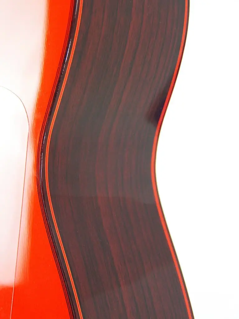 Nahaufnahme Der Seite Der Hermanos Conde 1999 Paco De Lucia Spezial Flamenco Gitarre, Die Die Holzmaserung, Die Roten Kanten Und Die Eleganten Kurven Vor Einem Weißen Hintergrund Zeigt.