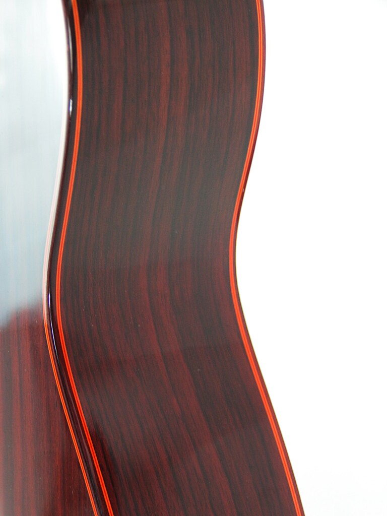 Nahaufnahme Der Seite Einer Hermanos Conde 1999 Paco De Lucia Spezial Flamenco-Gitarre, Die Die Dunkle Holzmaserung Mit Rötlich-Braunen Streifen Und Einer Glänzenden Oberfläche Vor Weißem Hintergrund Hervorhebt.