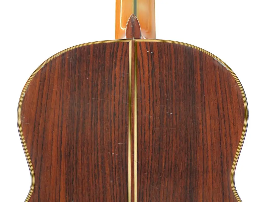 Nahaufnahme Der Rückseite Der Manuel Rodriguez Jr Klassische Gitarre Mit Reicher Dunkler Holzmaserung, Mittelnaht, Heller Verzierung Und Einigen Sichtbaren Kratzern.