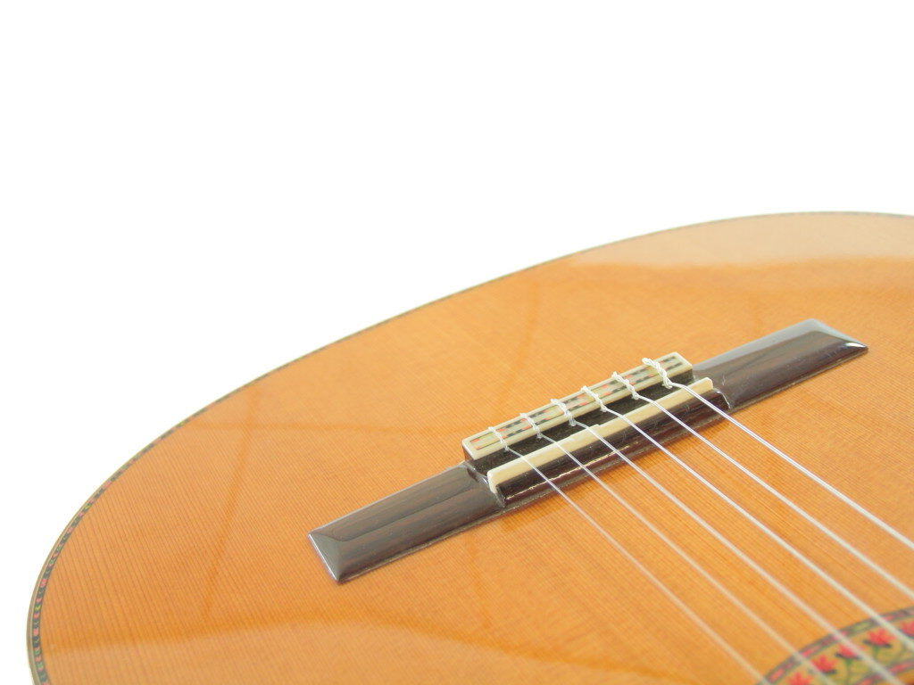 Nahaufnahme Des Korpus Und Stegs Der Manuel Rodriguez Jr Klassische Gitarre Mit Saiten Und Holzoberfläche Vor Einem Schlichten Weißen Hintergrund.