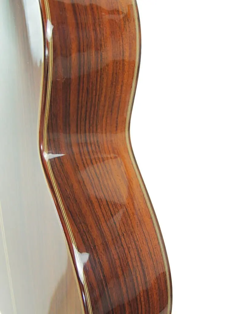 Nahaufnahme Der Seite Der Manuel Rodriguez Jr Klassische Gitarre, Die Ihre Polierte Dunkle Holzmaserung, Das Glänzende Finish Und Die Dekorativen Verzierungen Vor Einem Weißen Hintergrund Zeigt.