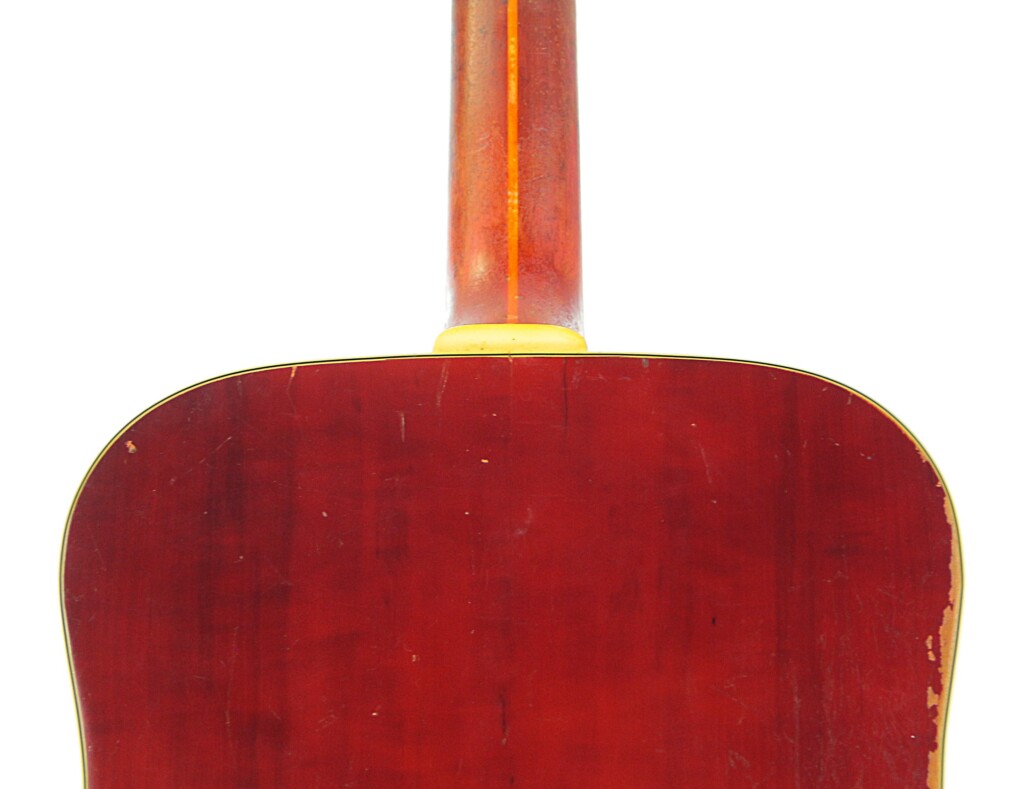 Close-Up Of The Guild D-44 1967 Acoustic Guitar Back, Featuring A Reddish Wood Finish With Edge Scratches And Wear, Highlighted By Yellow Trim Outlining The Body.
