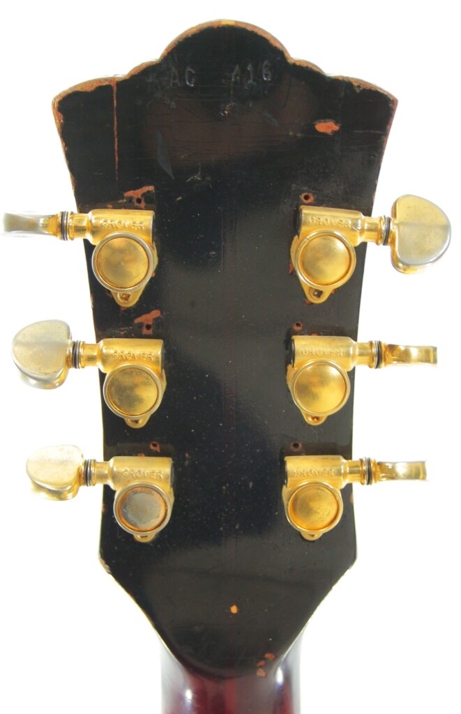 Close-Up Of The Guild D-44 1967 Acoustic Guitar Headstock Back, Featuring Six Gold Tuning Pegs, Visible Wear On The Black Finish, And Engraved Numbers And Letters At The Top.