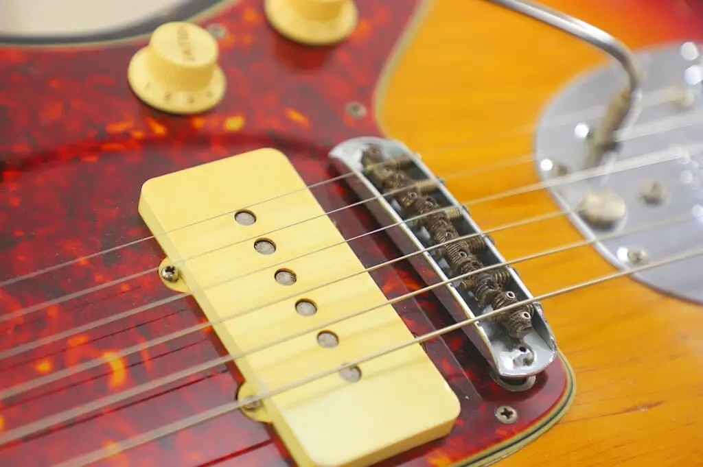 Close-Up Of The Fender Jazzmaster 1963 Electric Guitar Highlights Its Pickup, Bridge, Control Knobs, Visible Strings, And Distinctive Red Tortoiseshell Pickguard.