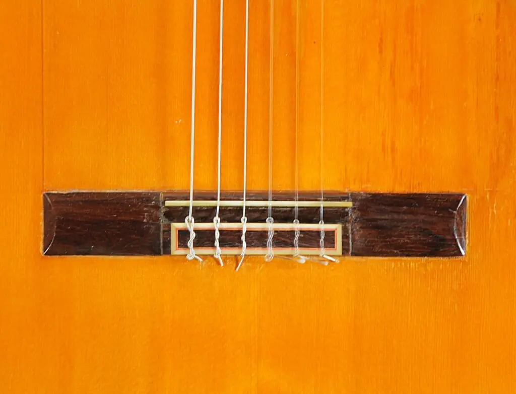 Close-Up Of The Bridge And Strings Of A Hermanos Conde 1966 Faustino Conde Flamenco Guitar, Highlighting The Wood Grain, Fine Details Of The Body, And Intricate String Ties.