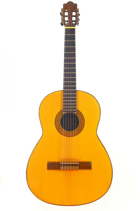 The Miguel Rodriguez 1960s Classical Guitar features a light wooden body, dark fretboard, and six strings, shown upright against a white background.