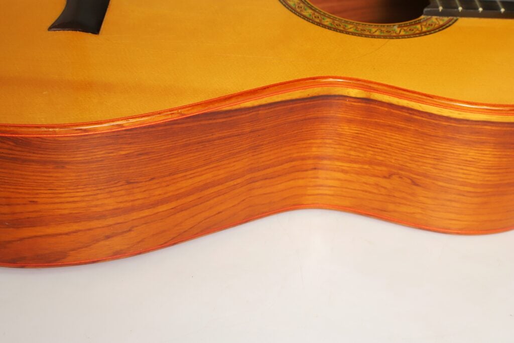 Nahaufnahme des Korpus einer Flamenco-Gitarre von Gerardo Escobedo aus dem Jahr 2018, die die Seite und die Decke mit einer dekorativen Rosette zeigt. Nahaufnahme des Korpus einer Flamenco-Gitarre von Gerardo Escobedo aus dem Jahr 2018, die die Seite und die Decke mit einer dekorativen Rosette zeigt.