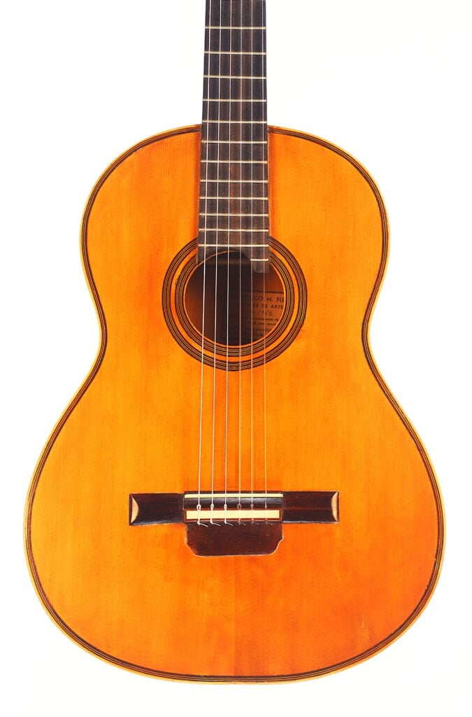 Die Francisco Manuel Fleta 1962 ist eine klassische Akustikgitarre mit Holzkorpus und sechs Saiten, die vor einem schlichten weißen Hintergrund fotografiert wurde. Die Francisco Manuel Fleta 1962 ist eine klassische Akustikgitarre mit Holzkorpus und sechs Saiten, die vor einem schlichten weißen Hintergrund fotografiert wurde.