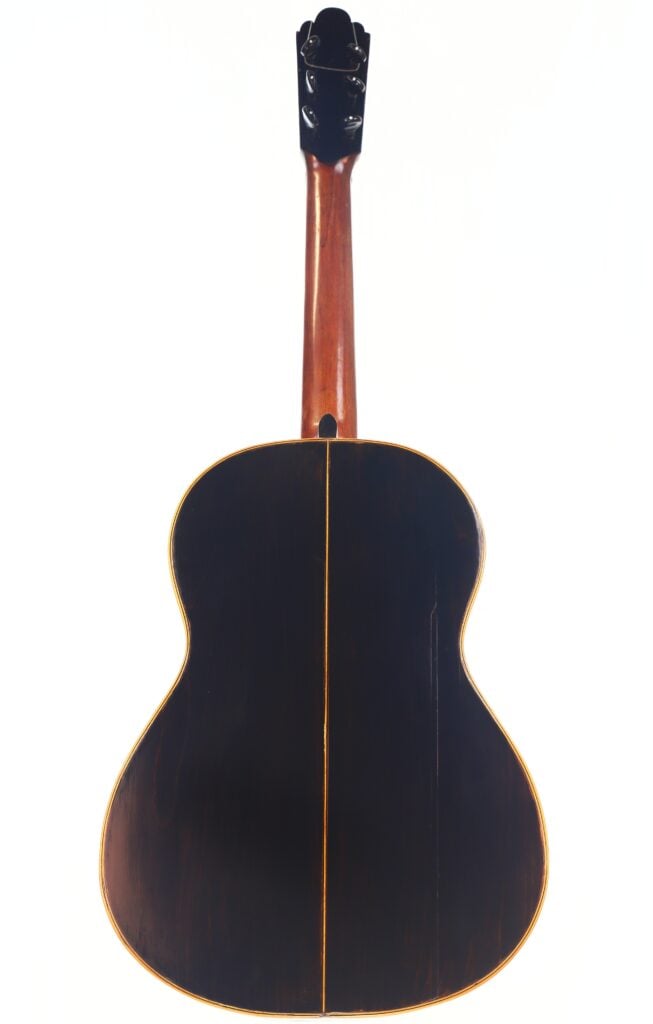 Das Foto zeigt die Rückseite einer Akustikgitarre von Francisco Manuel Fleta aus dem Jahr 1962 mit dunklem Holzfinish, hellem Hals und schmalem Mittelstreifen am Korpus vor einem weißen Hintergrund. Das Foto zeigt die Rückseite einer Akustikgitarre von Francisco Manuel Fleta aus dem Jahr 1962 mit dunklem Holzfinish, hellem Hals und schmalem Mittelstreifen am Korpus vor einem weißen Hintergrund.