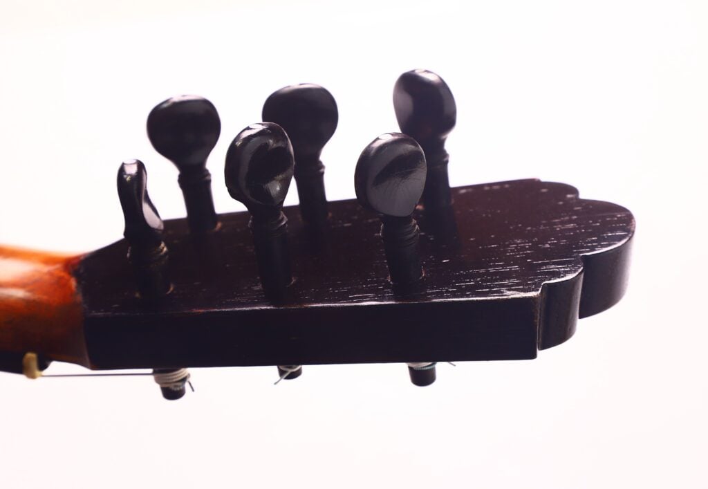 Nahaufnahme der Stimmwirbel an der Kopfplatte einer Gitarre von Francisco Manuel Fleta aus dem Jahr 1962. Das dunkle, leicht glänzende Holz steht vor einem weißen Hintergrund. Nahaufnahme der Stimmwirbel an der Kopfplatte einer Gitarre von Francisco Manuel Fleta aus dem Jahr 1962. Das dunkle, leicht glänzende Holz steht vor einem weißen Hintergrund.