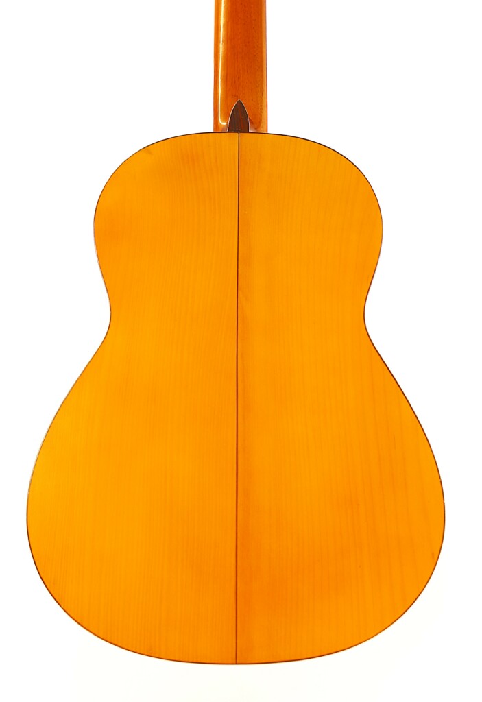 The Image Displays The Back Of A Manuel G. Mayoral 1980 Flamenco Guitar Crafted From Polished Light Wood, Featuring A Curved Body And A Vertical Center Seam, All Set Against A White Background.