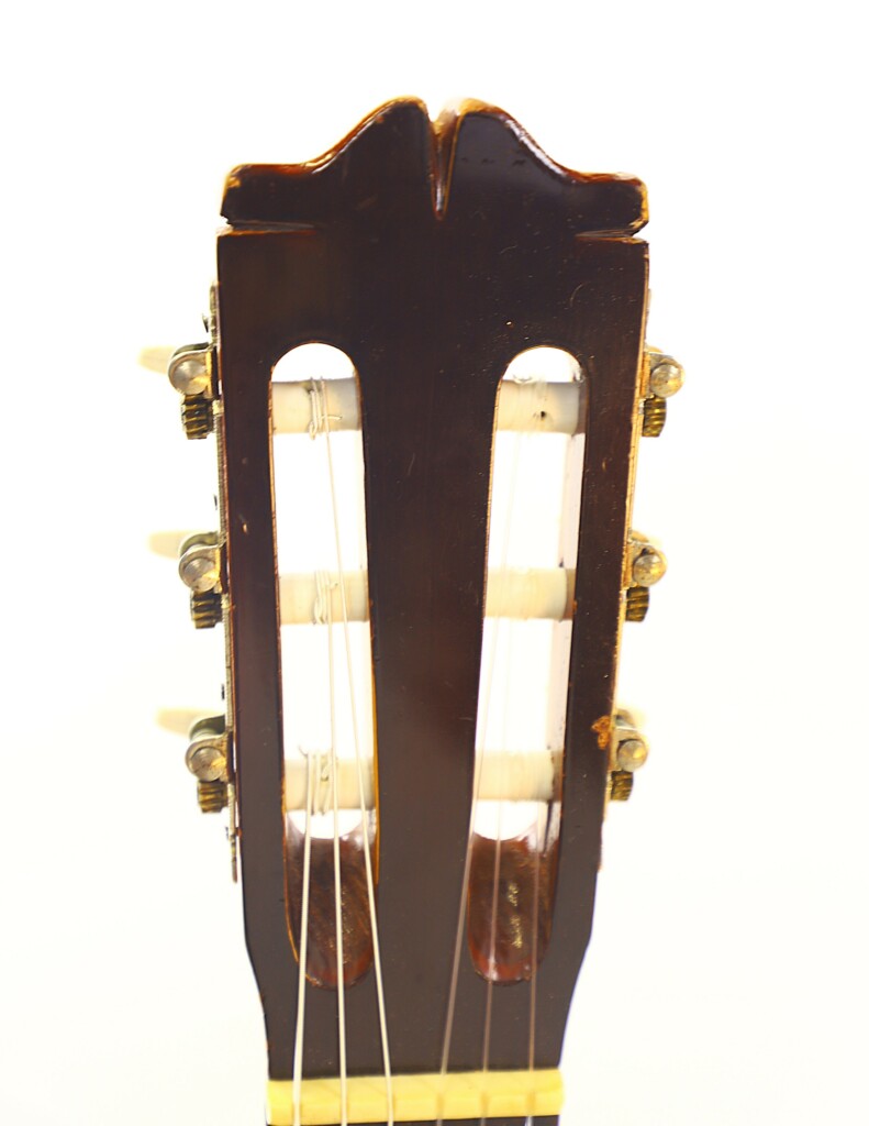 Close-Up Of The Headstock Of The Manuel G. Mayoral 1980 Flamenco Guitar, Featuring Tuning Pegs, Strings, And A Dark Wood Surface With Two Vertical Slots, Set Against A White Background.