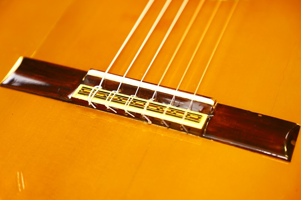 Close-Up Of The Bridge And Strings On A Manuel G. Mayoral 1980 Flamenco Guitar, Showcasing Intricate Woodwork And String Detail Set Against Its Warm, Golden-Brown Body.