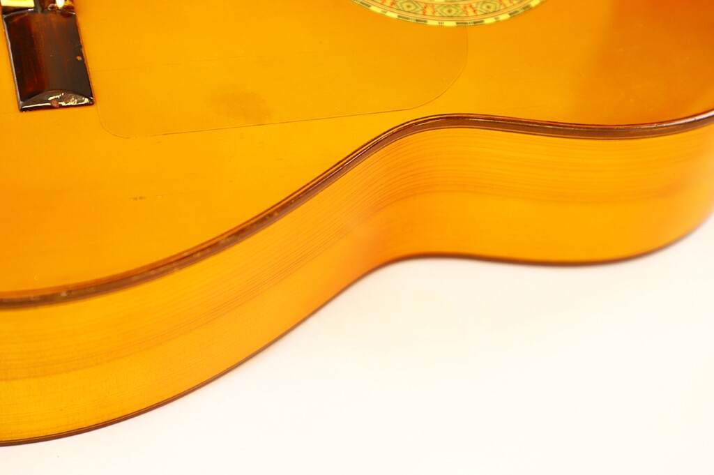 Close-Up Of The Side And Top Of A Manuel G. Mayoral 1980 Flamenco Guitar, Highlighting The Wood Grain, Curves, And Part Of The Decorative Sound Hole.