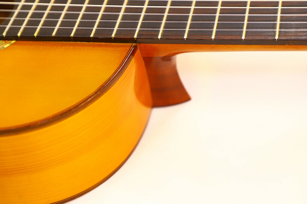 Close-Up Of The Manuel G. Mayoral 1980 Flamenco Guitar, Highlighting Its Body And Neck With Visible Wood Grain, Strings, And Frets Against A Plain Light Background.