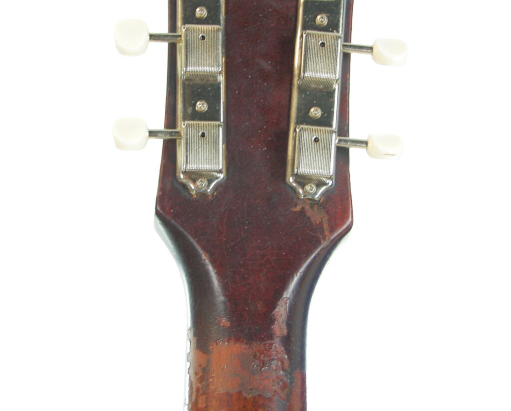 Close-Up Of The Gibson J-45 1955 Acoustic Guitar Headstock Back, Highlighting Tuning Pegs, Worn Neck, And Its Glossy Dark Brown Finish.