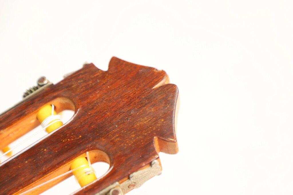 Close-Up Of The Marcelino López Nieto 1954 Flamenco Guitar Headstock, Featuring Visible Tuning Pegs And Yellow Strings Set Against A White Background.