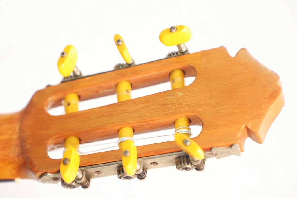 Close-Up Of The Tuning Pegs On A Marcelino López Nieto 1954 Flamenco Guitar, Featuring Six Yellow Tuning Keys And Wound Strings Against A White Background.