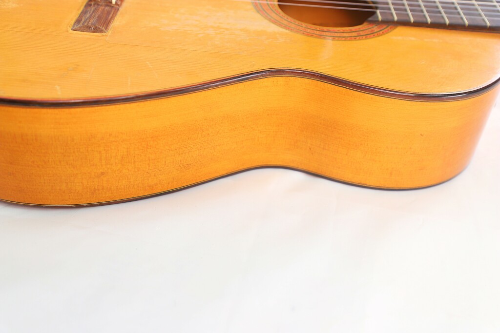 Close-Up Of The Marcelino López Nieto 1954 Flamenco Guitar’s Side And Lower Body, Highlighting Its Natural Wood Grain And Elegant Curves Against A White Background.