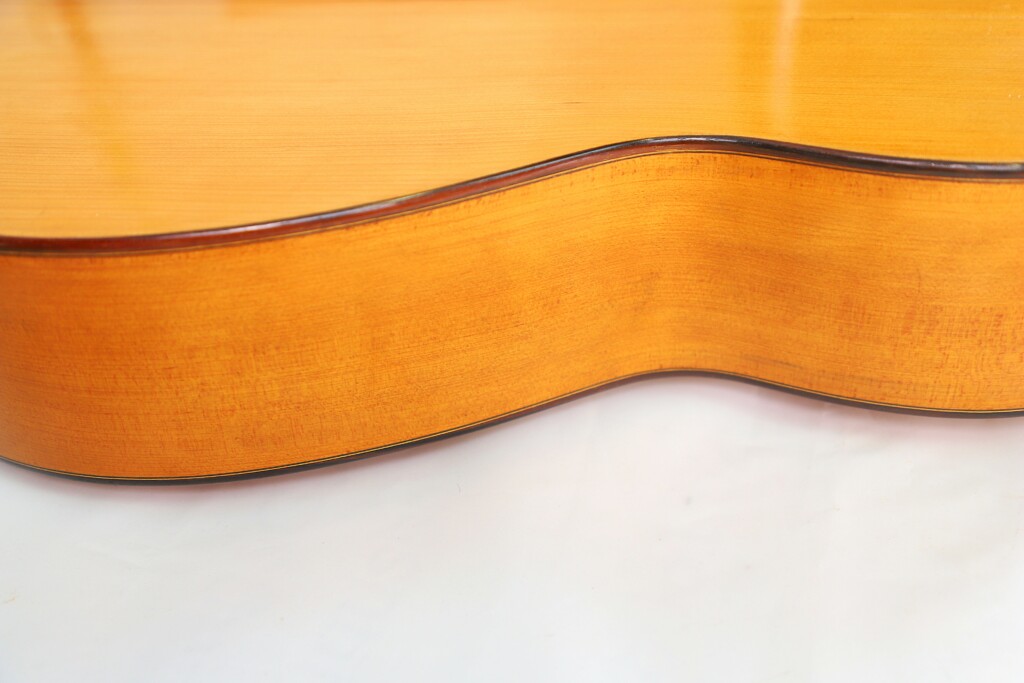 Close-Up Of The Side And Top Of A Marcelino López Nieto 1954 Flamenco Guitar, Highlighting Its Light Brown Polished Wood Grain Against A White Background.