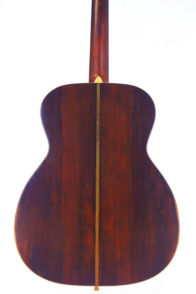 The Back Of The Martin Om-28 1931 Acoustic Guitar Features Dark, Polished Wood With A Center Seam, Shown Against A White Background.