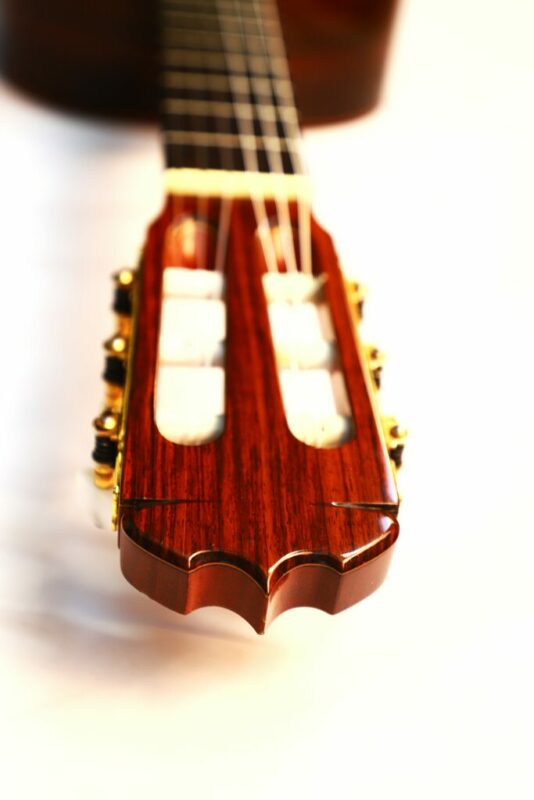 Close-up of the José Ramírez 1a 1987 classical guitar headstock with gold tuners, showcasing the wood grain and strings in sharp detail, fading into a softly blurred neck in the background.