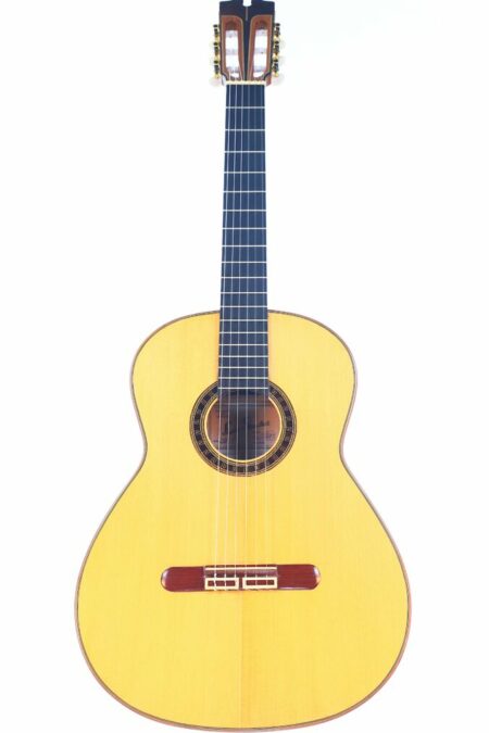 The Luis Sanchez 2021 Negra Flamenco Guitar, featuring a light wooden body, dark fingerboard, and six strings, is pictured against a white background.