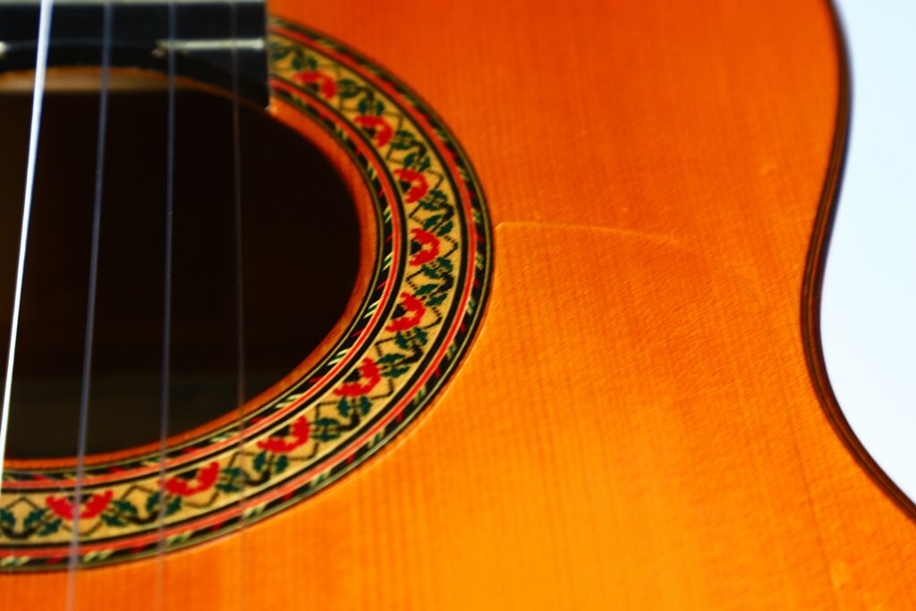 Close-Up Of The Lorenzo Alvarez 1982 Flamenco Guitar, Highlighting The Ornate Red, Green, And Black Rosette Around The Soundhole On Its Wooden Body, With Guitar Strings Partially Visible On The Left.