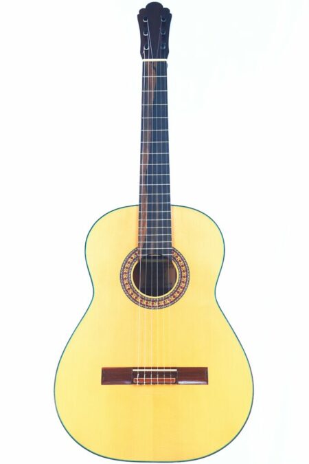 The Sergio Sanchez 2024 Negra Flamenco Guitar features a light wood body, dark wood bridge, ornate rosette around the sound hole, and a dark fretboard, shown against a white background.