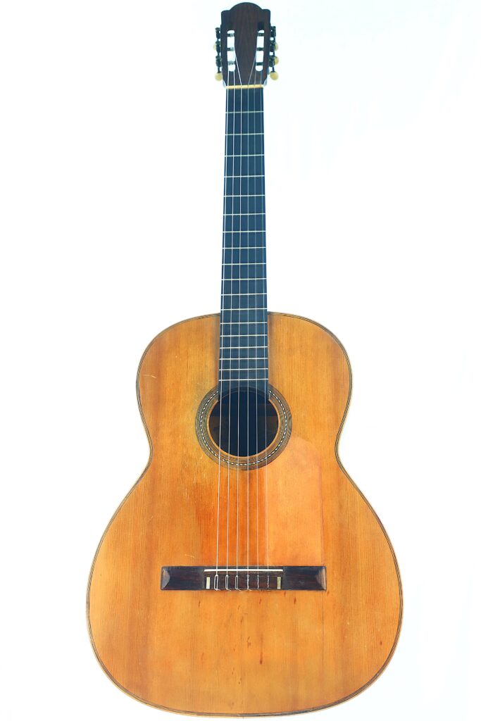 The Salvador Ibanez ~1900 Classical Guitar Features A Wooden Body, Six Strings, And A Dark Fretboard, Displayed Upright Against A Plain White Background.