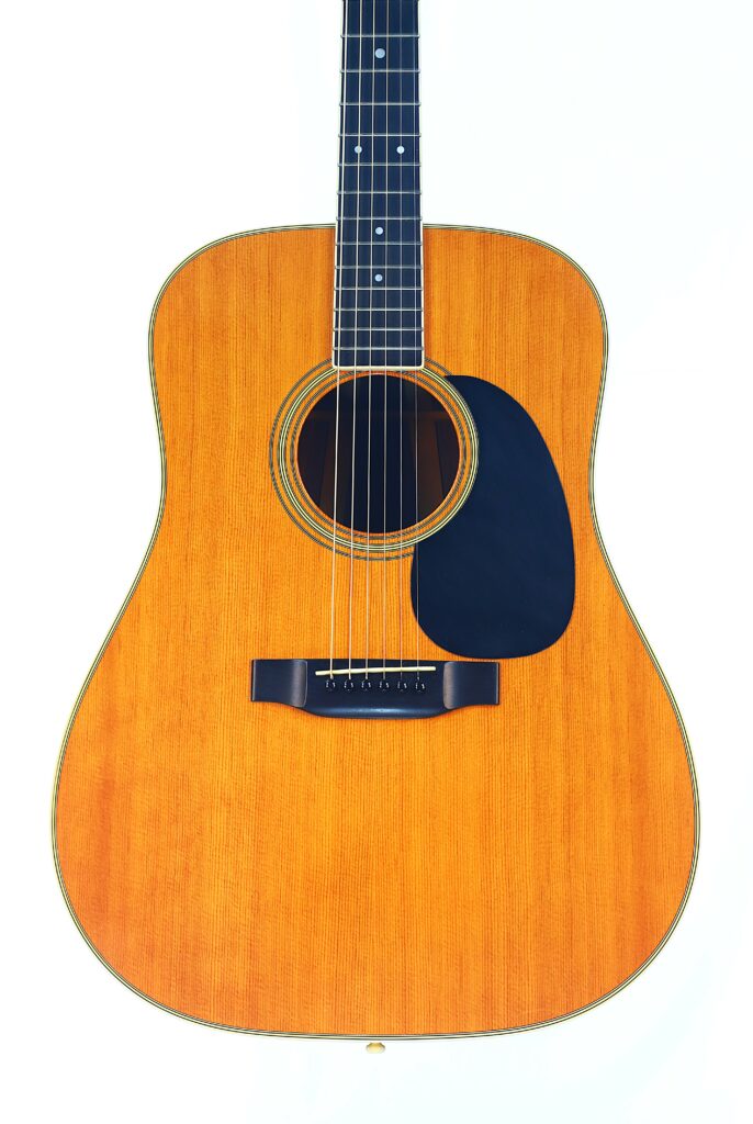 A Close-Up Of The Martin D-35 1979 Acoustic Guitar Features A Wooden Body, Black Pickguard, And Steel Strings Set Against A White Background.