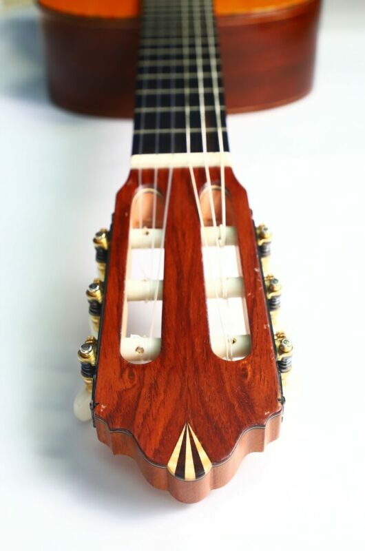 Close-up of the headstock and neck of the Andrés Marvi 2021 Negra Flamenco Guitar on a white surface, highlighting the tuning pegs and strings.