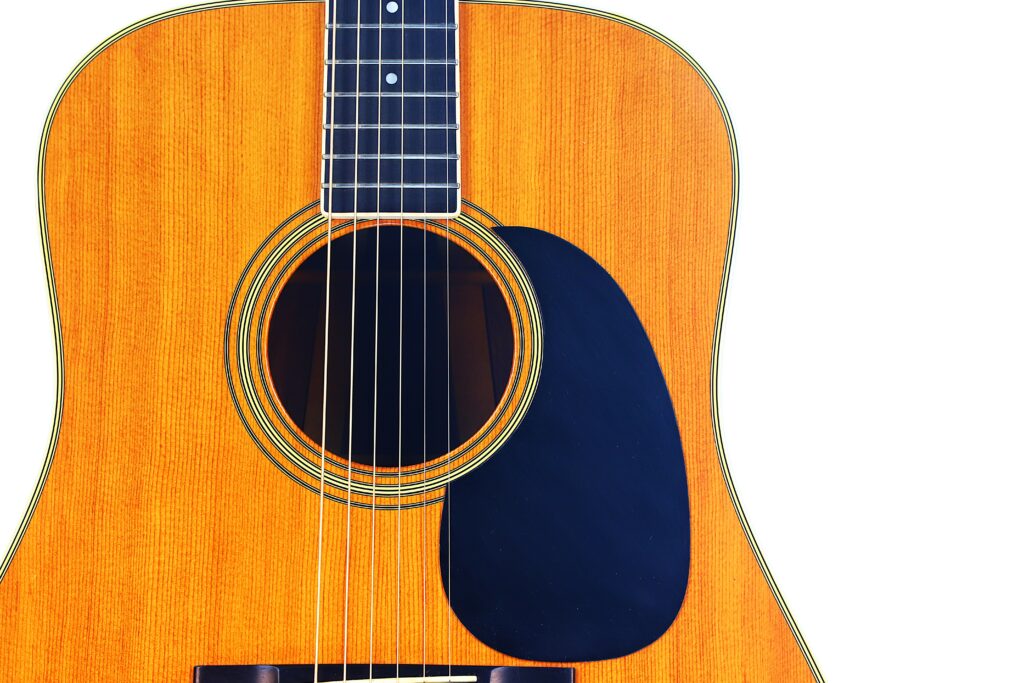 Close-Up Of A Martin D-35 1979 Acoustic Guitar Body, Featuring The Sound Hole, Strings, And Black Pickguard On A Light Wood Surface Against A White Background.
