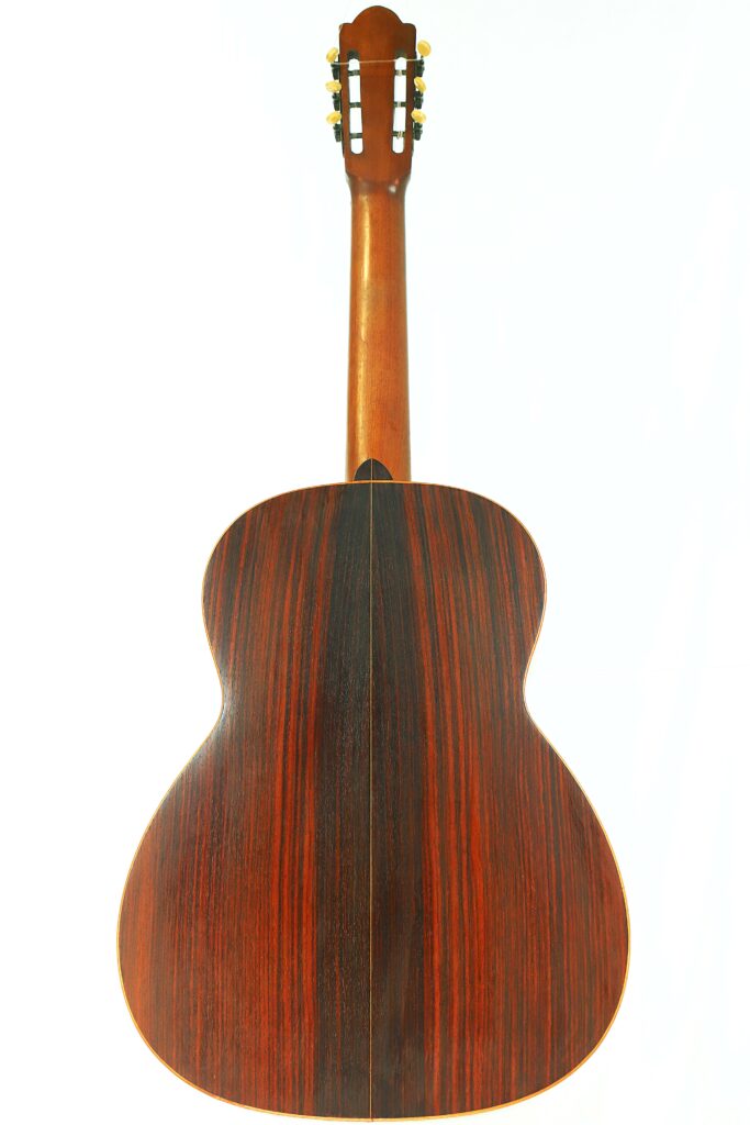 The Salvador Ibanez ~1900 Classical Guitar Is Photographed From The Back, Highlighting Its Smooth Wooden Finish With Dark And Reddish-Brown Vertical Grain Patterns Against A White Background.