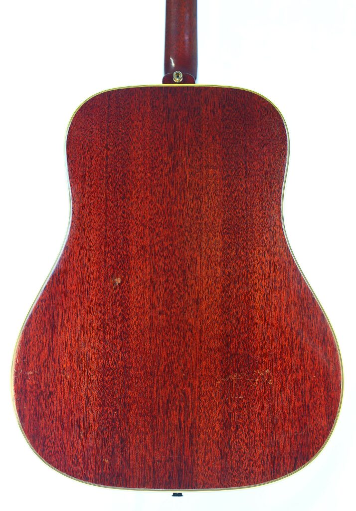 Das Bild Zeigt Den Boden Einer Gibson Hummingbird 1966 Akustik Gitarre Mit Einer Satten Rotbraunen Holzmaserung Und Leichtem Binding An Den Rändern. Die Glatte Oberfläche Weist Ein Paar Kleine, Naturbelassene Holzfehler Auf.